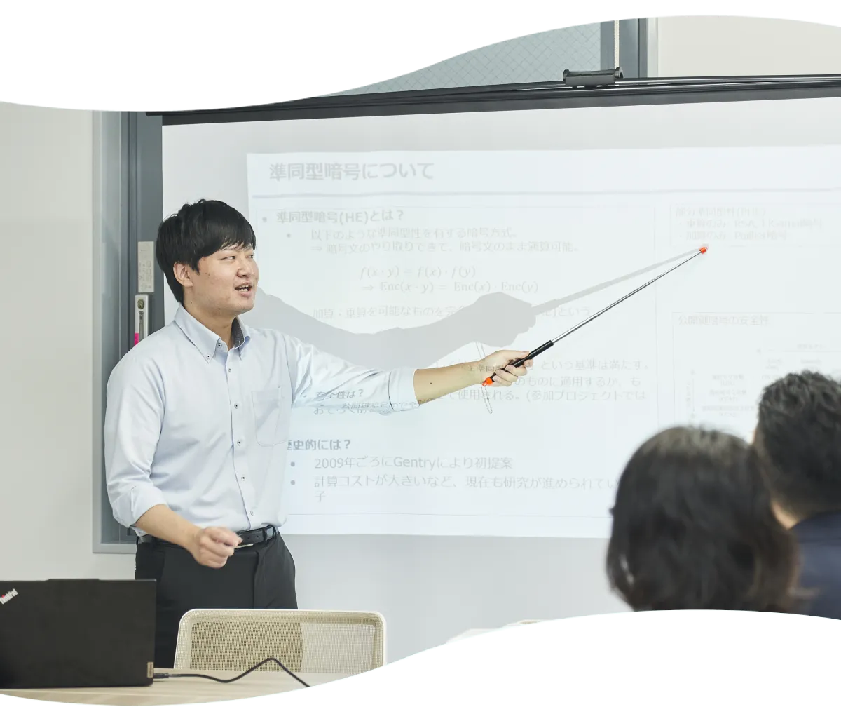 スクリーンに映した資料を指し示して説明するT.M