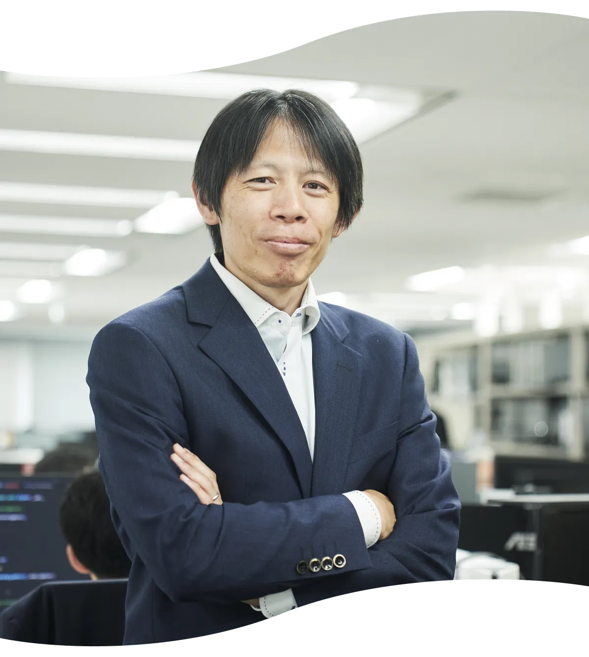 腕を組んでオフィスに立つY.K